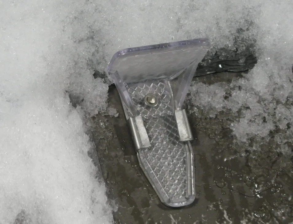 Pad-style snow guard attached to a stainless steel strap on a composite tile roof