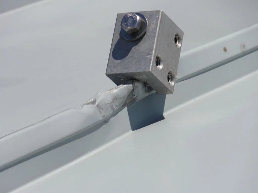 Cantilevered snow rail clamp system deforming a standing seam under load