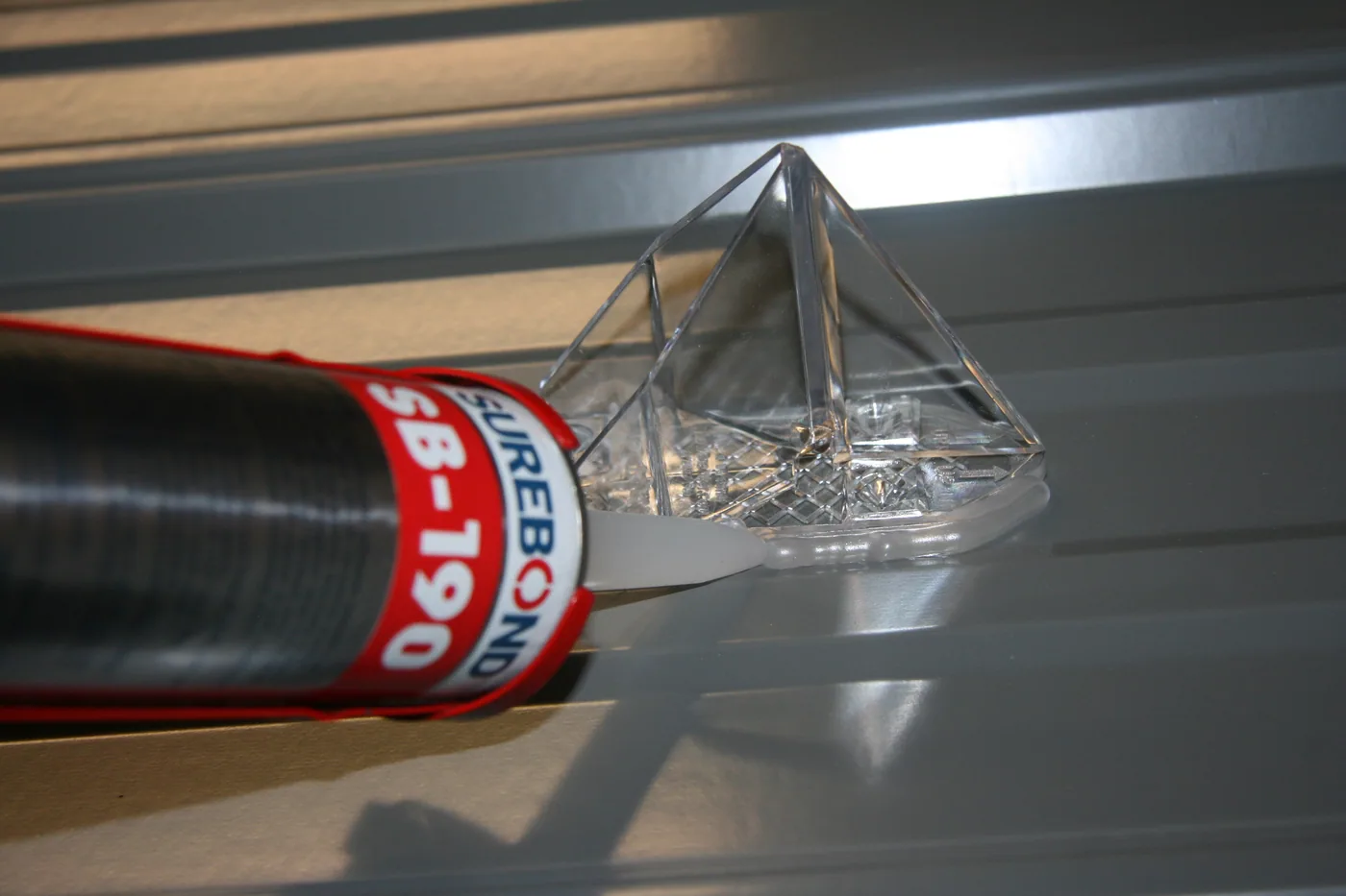 a pointed snow breaker style guard being installed with clear VHB tape with a bead of Surebond SB190 around the perimeter