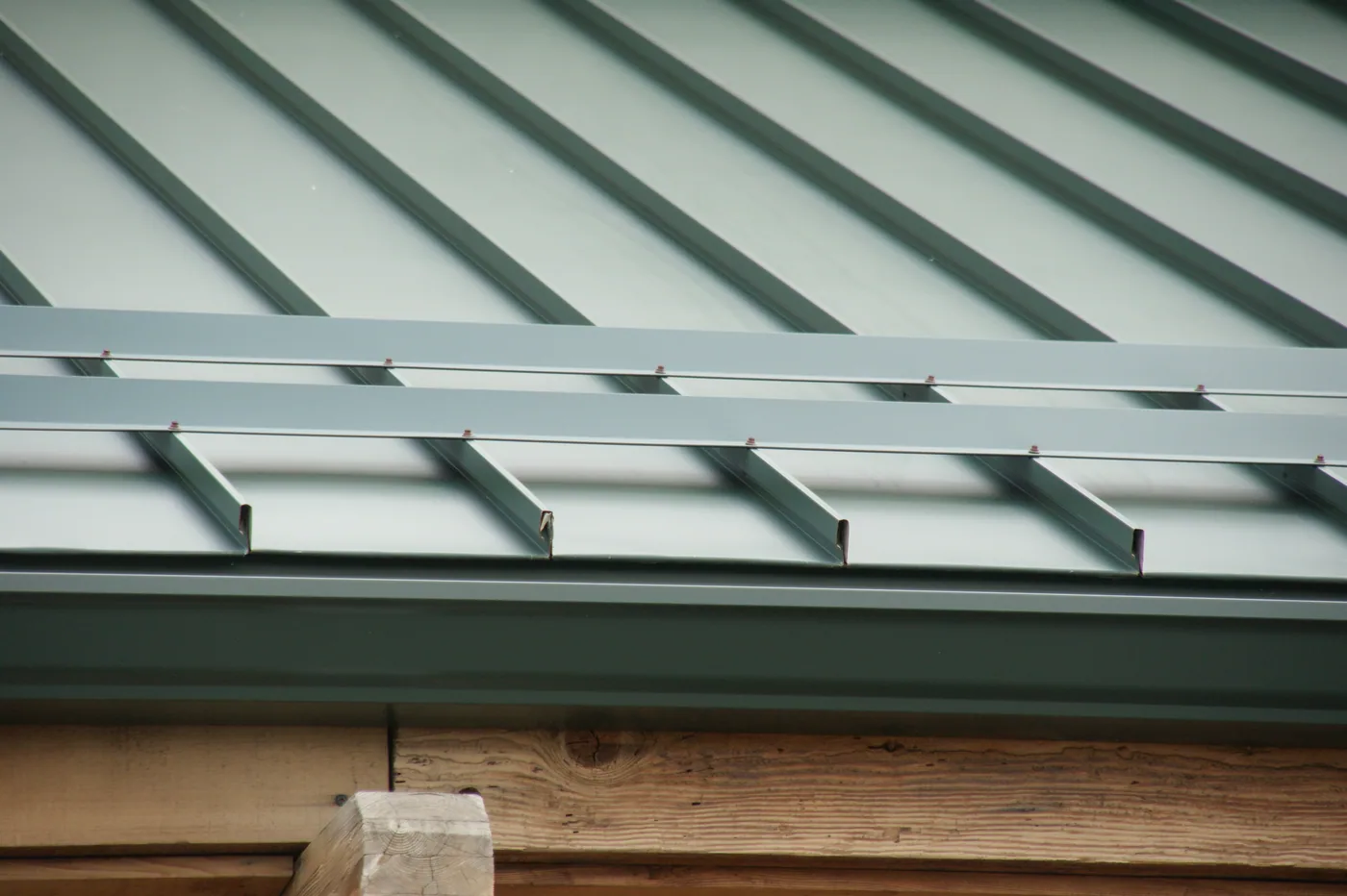 Close view of screws penetrating a standing seam for an improvised snow retention angle